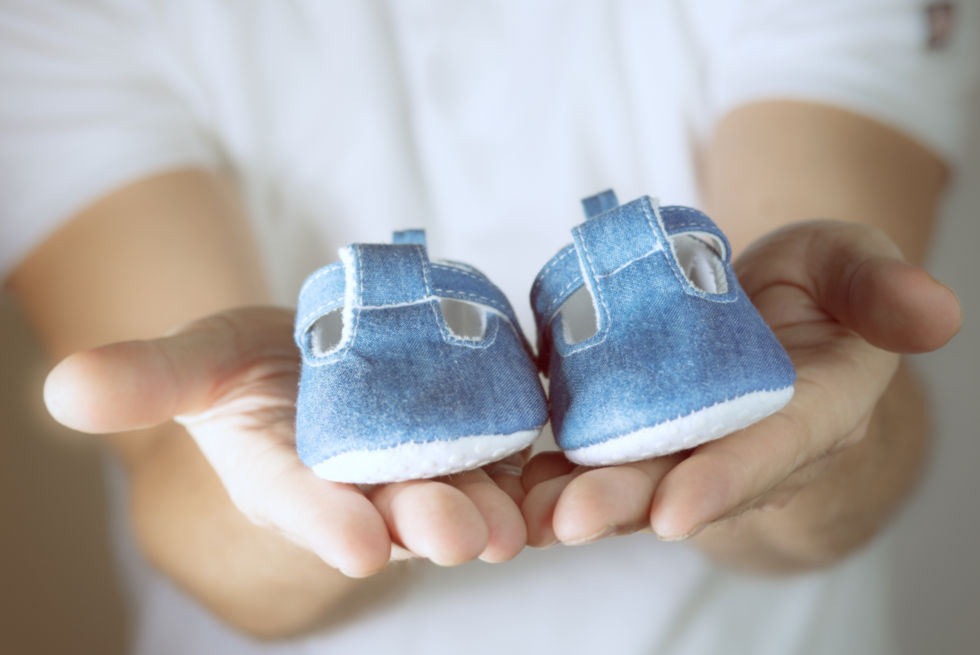 Foto mit Babyschuhen auf zwei Händen